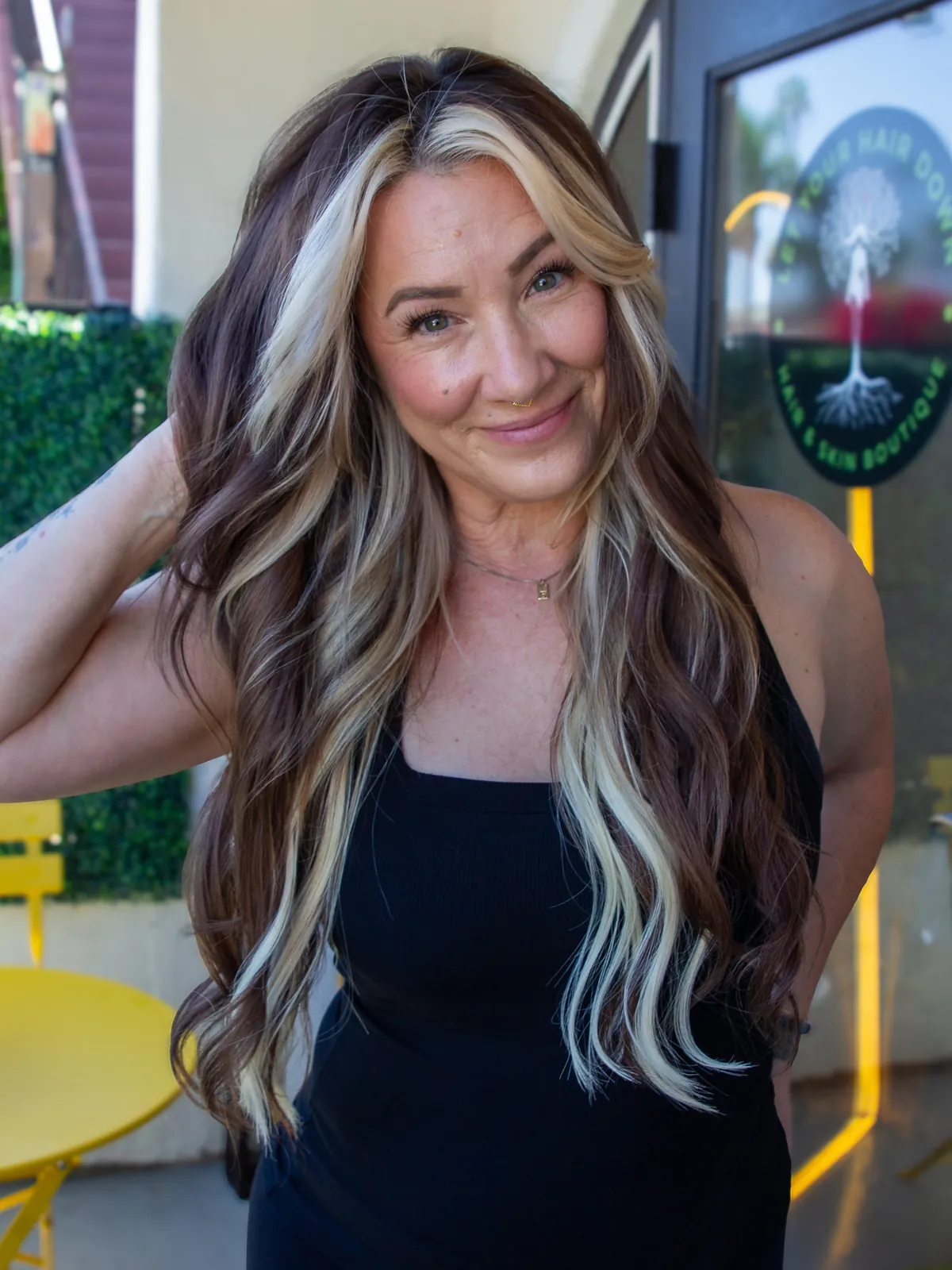 After: long brunette waves with blonde pieces framing the face and running through the lengths.