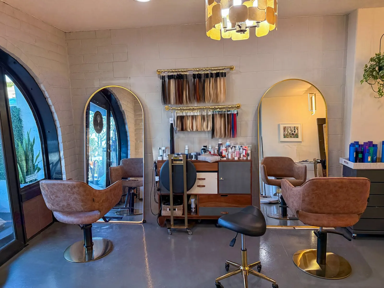 The salon interior, arch doorway and arch mirrors, leather chairs on brass bases.