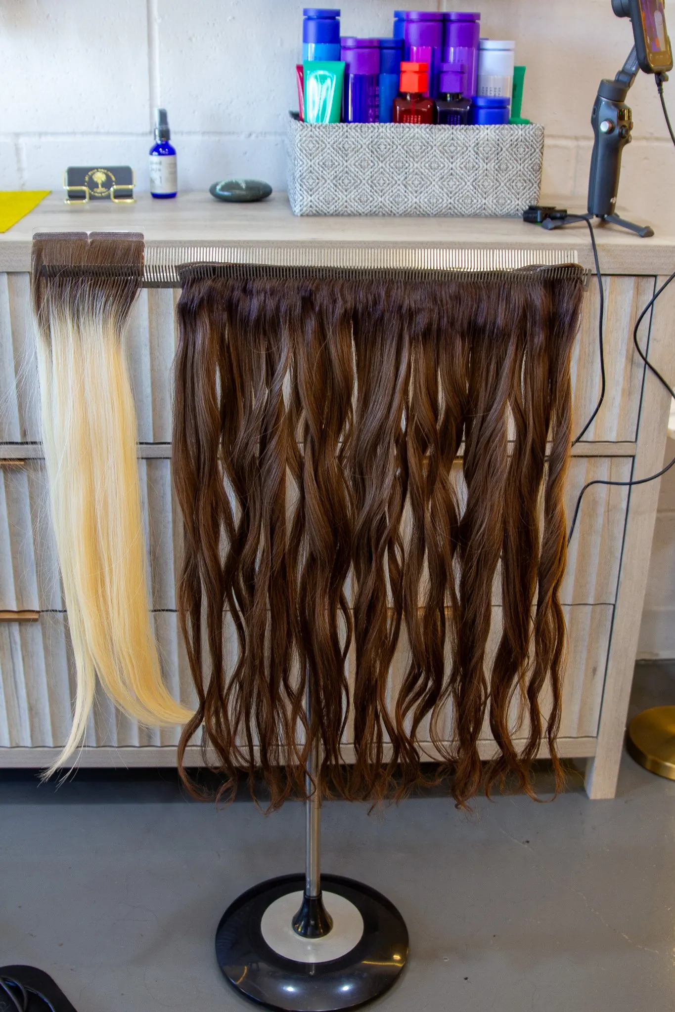 Weft hair hanging on a salon rack, a range of lengths and tones side by side.
